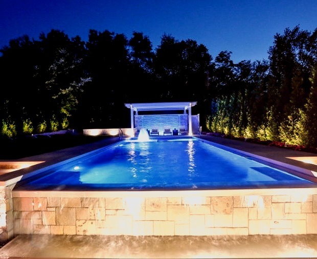 Photo of a rectangular lap pool in a medium-sized, elegant backyard with stones.